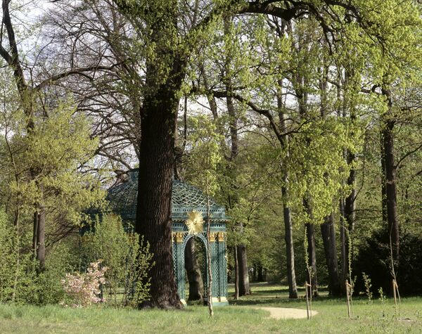 Blick zur Gitterlaube des Rehgartens im Park Sanssouci durch blühende Bäume