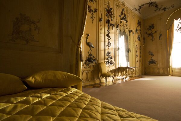 Vue sur la quatrième chambre d'hôtes du château Sanssouci aux murs jaunes et textiles et aux murs décorés d'or