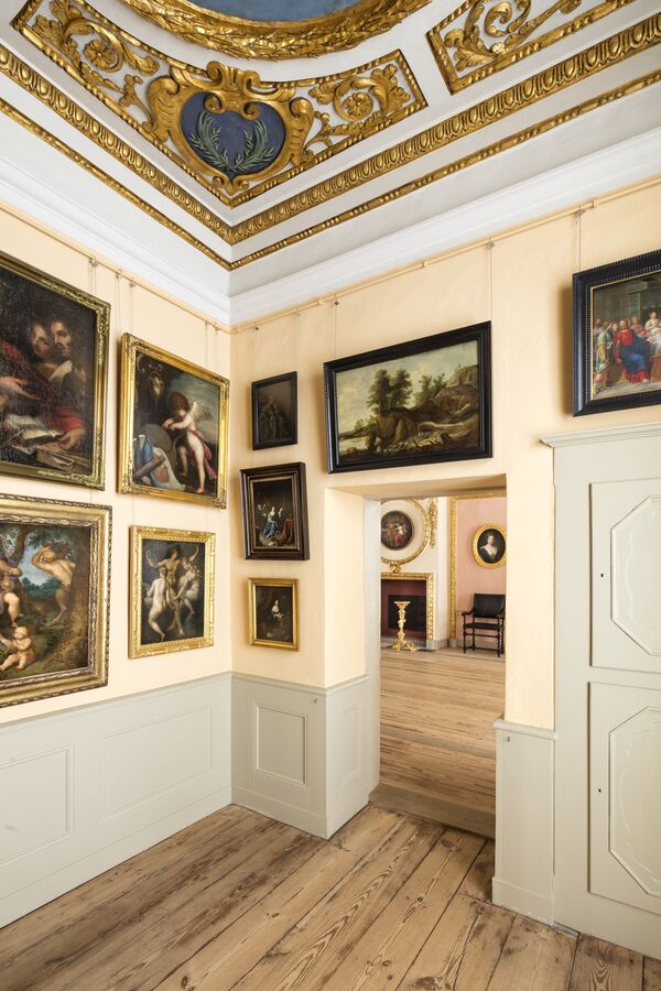 Raumansicht eines Kabinetts im Schloss Caputh mit vielen Gemälden