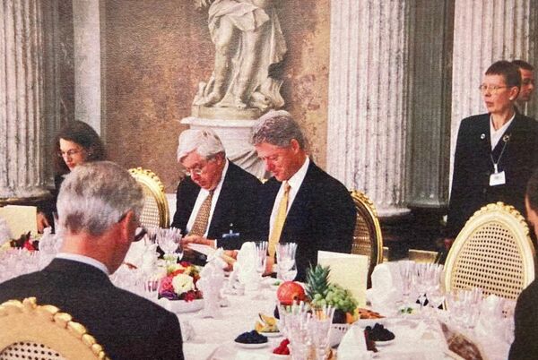 US-Präsident Bill Clinton studiert die Menüfolge des Mittagessens, neben ihm US-Botschafter John Kronblum.