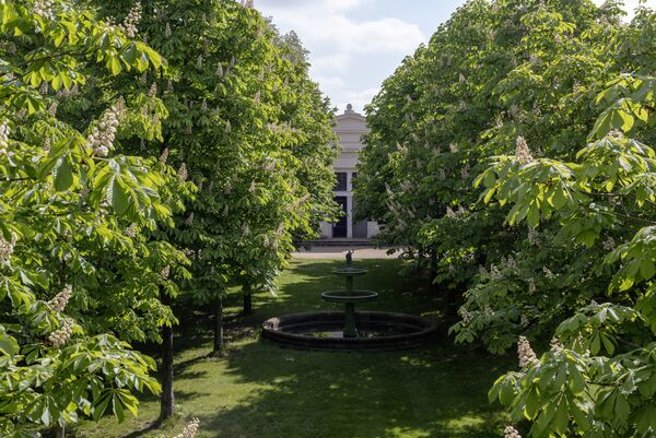 Blick durch blühende Kastanienbäume zum Schloss Charlottenhof 