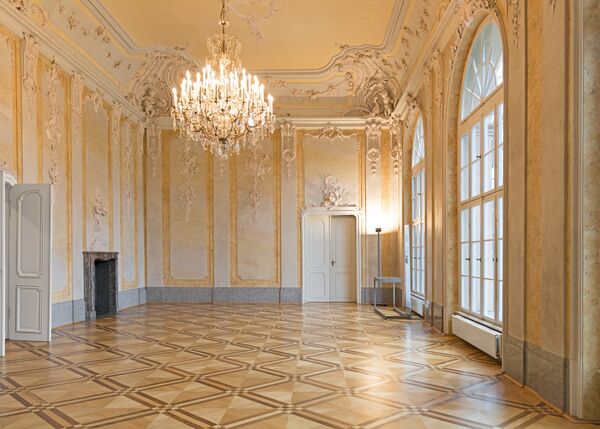 Blick in einen mit Stuck verzierten Saal mit Kronleuchter im Schloss Schönhausen