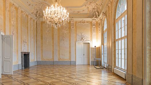 Blick in einen mit Stuck verzierten Saal mit Kronleuchter im Schloss Schönhausen