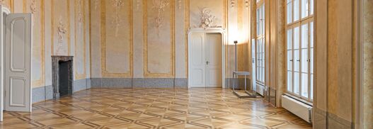 Blick in einen mit Stuck verzierten Saal mit Kronleuchter im Schloss Schönhausen