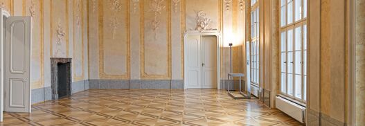 Blick in einen mit Stuck verzierten Saal mit Kronleuchter im Schloss Schönhausen