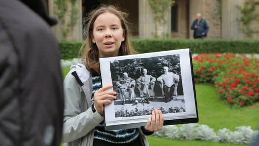 Führung „Unterm Sowjetstern“, Junge Frau hält Foto der „Großen Drei“ hoch, im Hintergrund der rote Stern vor Schloss Cecilienhof