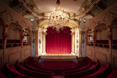 Schlosstheater im Neuen Palais von Sanssouci, schräger Blick zur Bühne mit geschlossenem Vorhang, bei abgedunkeltem Licht