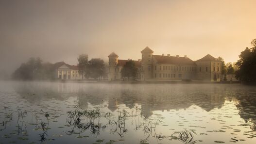 Blick über den Grienericksee auf das Schloss Rheinsberg im Abendlicht