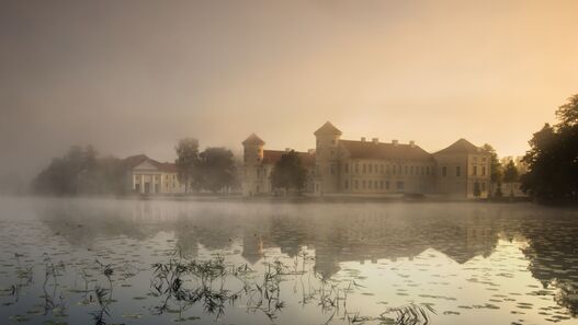 Blick über den Grienericksee auf das Schloss Rheinsberg im Abendlicht