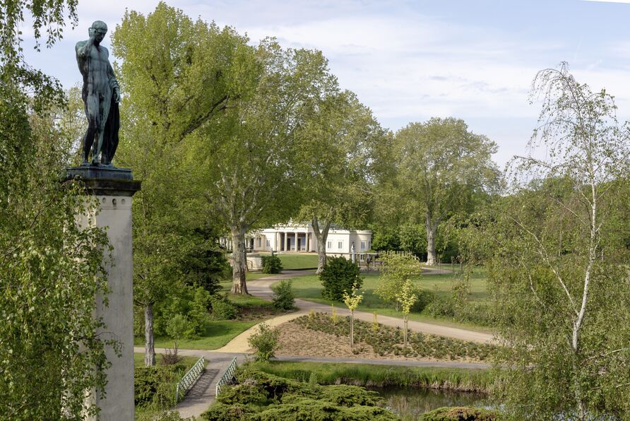 Blick auf Schloss Charlottenhof im Park Sanssouci, im Vordergrund die Bronzeplastik „Apoll“