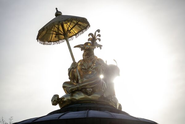 Goldene Skulptur eines sitzenden Mannes mit chinesischer Anmutung auf dem Dach des Chinesischen Hauses im Park Sanssouci 