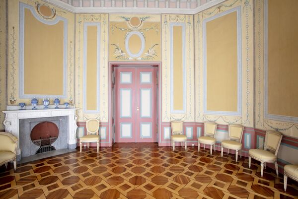 Raumansicht der Braunen Kammer im Marmorpalais mit gelb-rosa Wänden und gemustertem Parkett