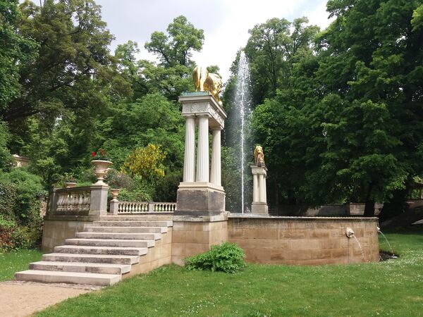 Blick auf den Löwenbrunnen im Park Glienicke mit goldenen Löwen und Fontäne