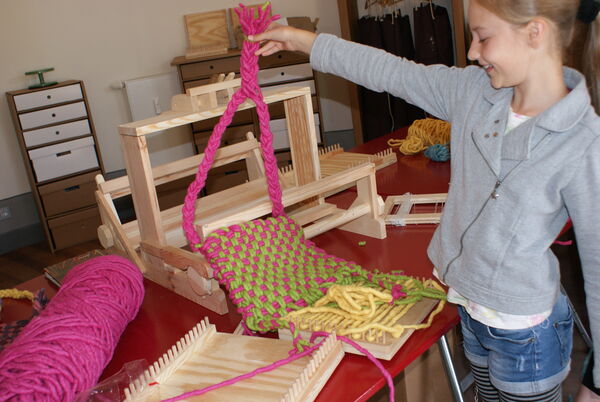 Museumswerkstatt am Schloss – Die am Webstuhl hergestellte Tasche © SPSG / Solvejg Kralik Museumswerkstatt am Schloss – Mädchen zeigt die am Webstuhl hergestellte Tasche