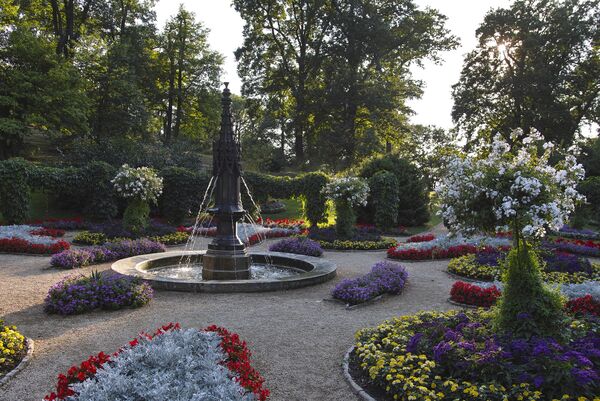 Blick in den Gotischen Garten mit bunt blühenden Blumenbeeten und Fontäne im Park Babelsberg