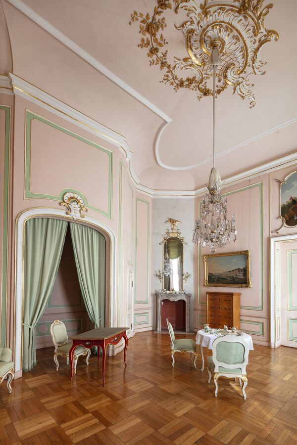 Blick in ein rosafarbenes Gästezimmer mit türkisen Stoffen in den Neuen Kammern von Sanssouci 