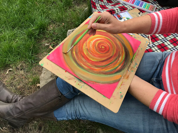 Frauenhände malen mit Pinsel eine Spirale