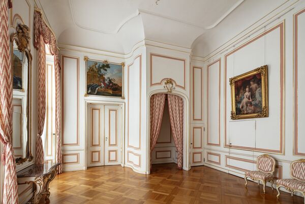 Blick in ein Gästezimmer mit rot-weißen Vorhängen in den Neuen Kammern im Park Sanssouci