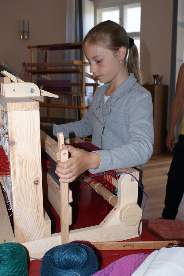 Museumswerkstatt am Schloss – Am Webstuhl © SPSG / Solvejg Kralik Museumswerkstatt am Schloss – Mädchen am Webstuhl