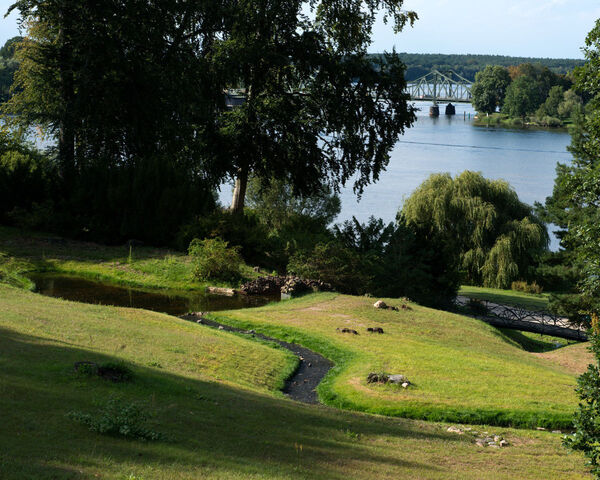 Wasserspiele im Park Babelsberg, im Hintergrund – teils von Bäumen verdeckt – die Glienicker Brücke