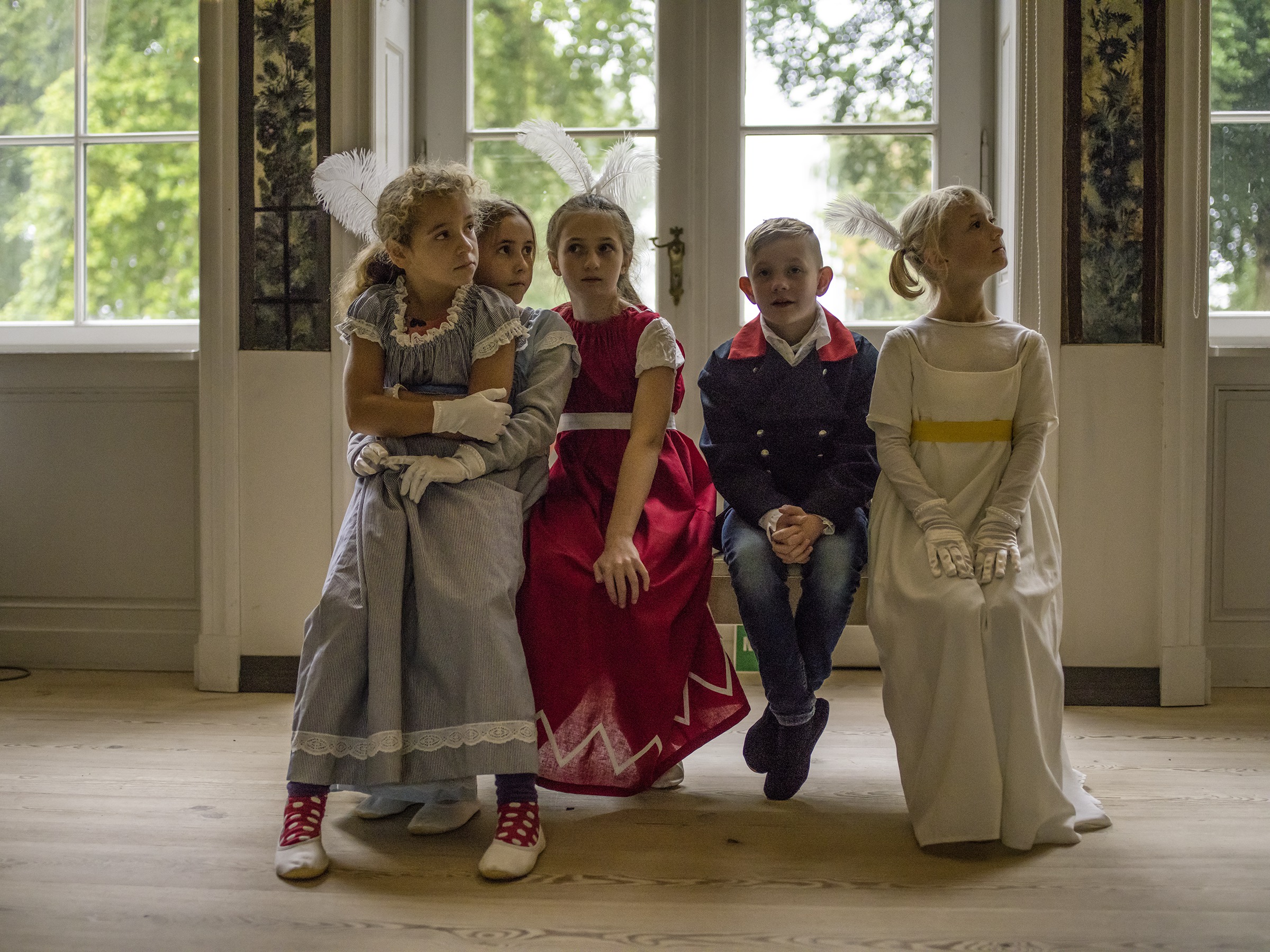 Kinderführung im Schloss Paretz, Vier königlich verkleidete Kinder sitzen aufeiner Bank im Gartensaal©  / 